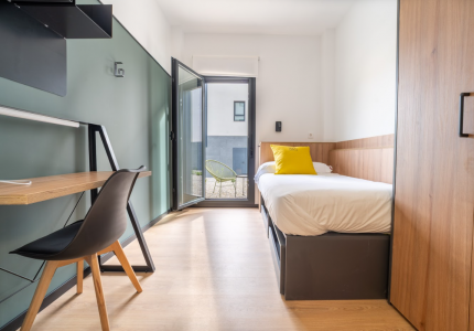 Habitación individual equipada en la residencia de estudiantes Bravo Students Murcia, con escritorio, cama y acceso a terraza