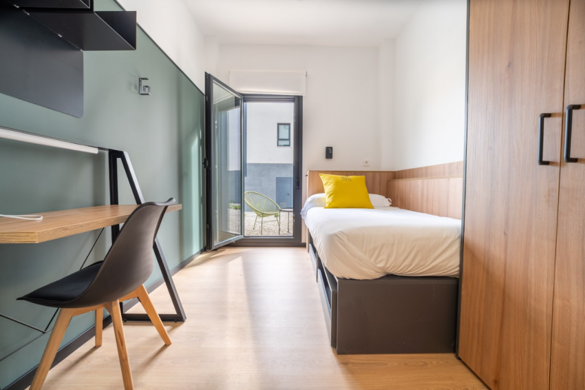 Habitación individual equipada en la residencia de estudiantes Bravo Students Murcia, con escritorio, cama y acceso a terraza