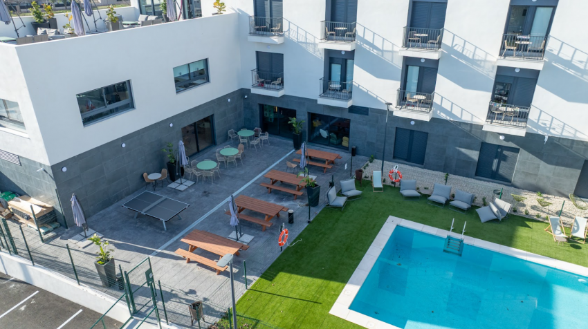 Vista aérea de la zona exterior de la residencia universitaria Bravo Students Murcia, con piscina, jardín y zonas de descanso